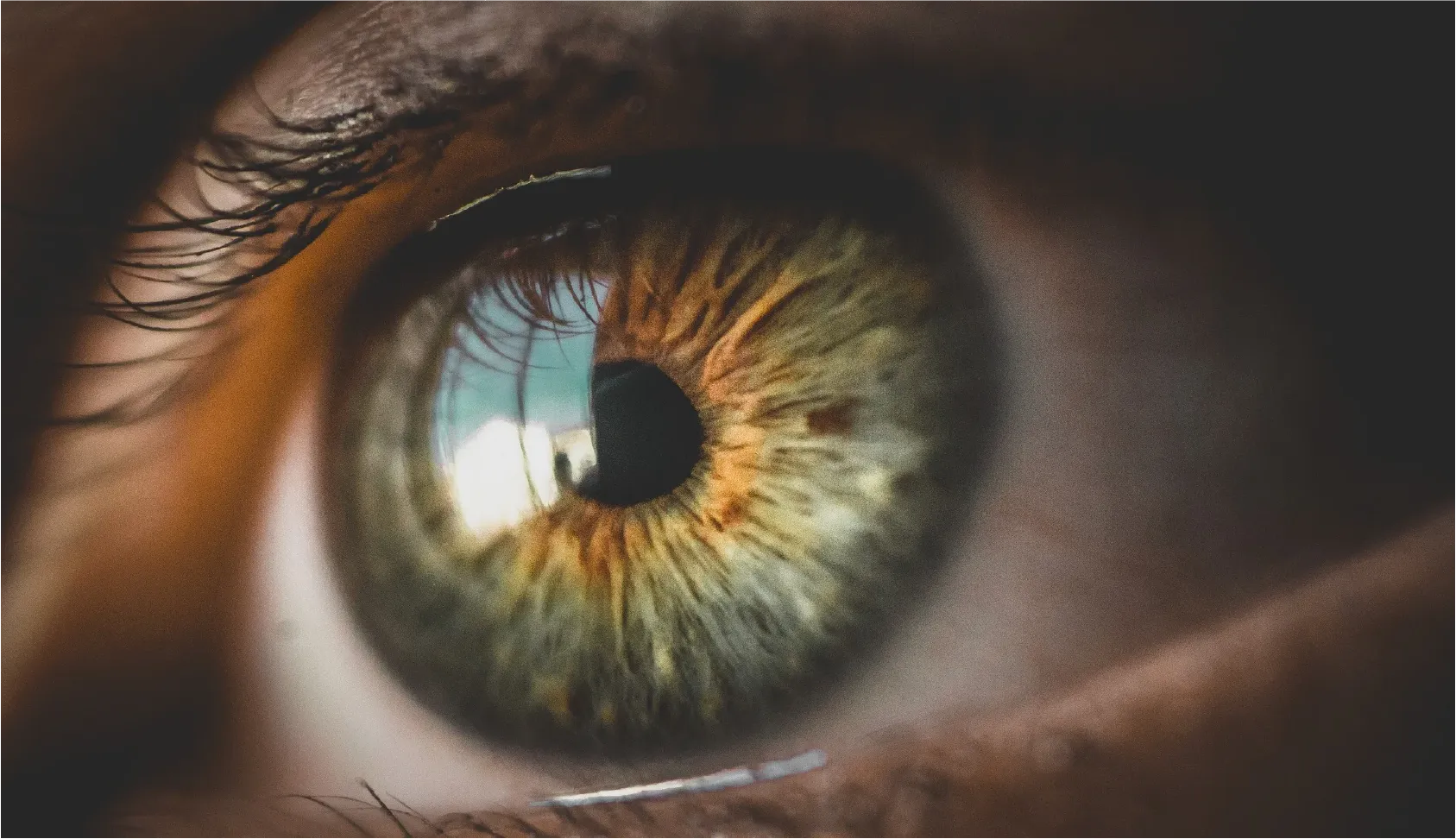 Close-up of a human eye showing detailed iris textures and reflections, emphasizing focus or perspective