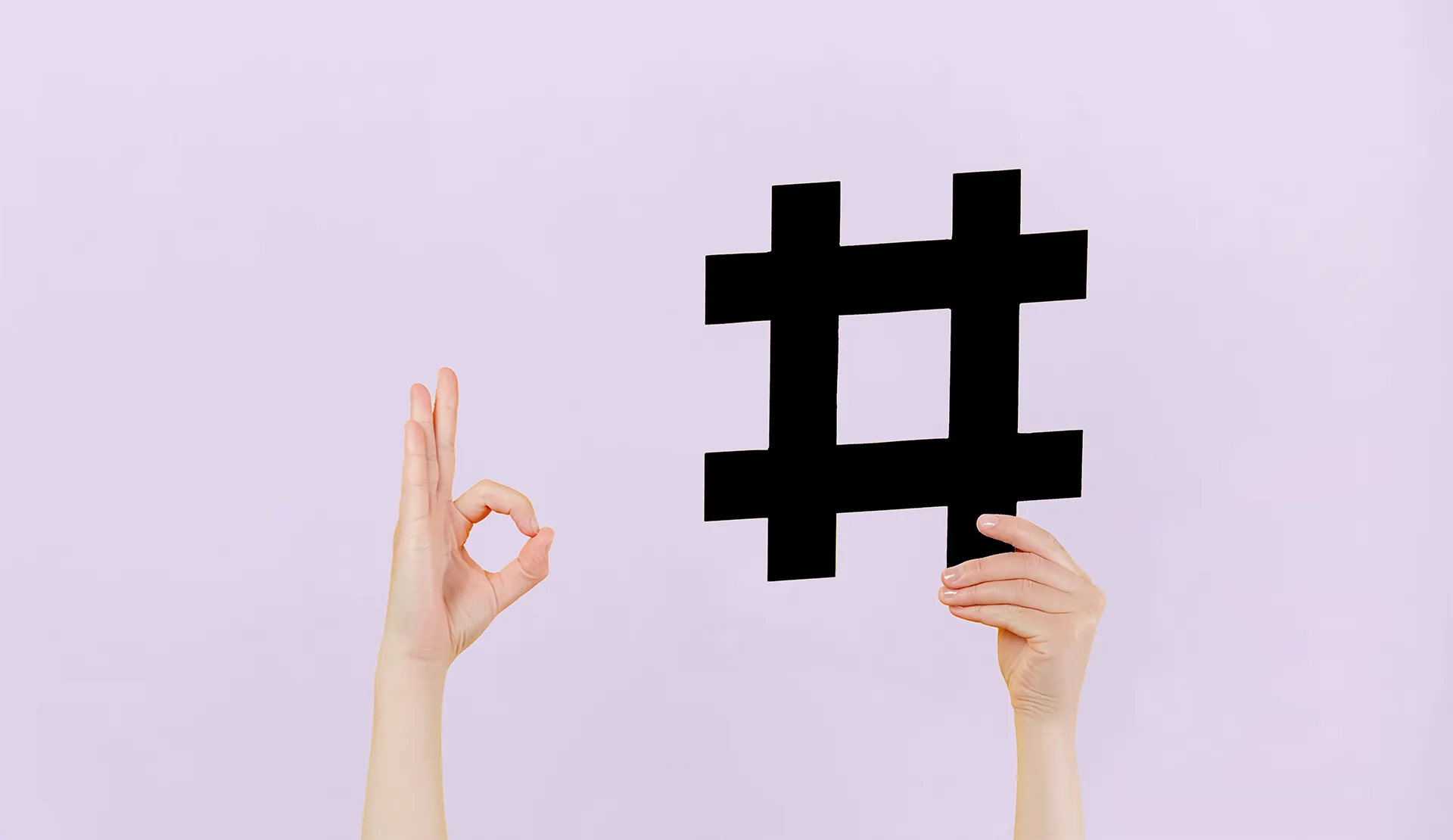 Two hands holding a large hashtag symbol against a plain background, symbolizing social media or trending topics.