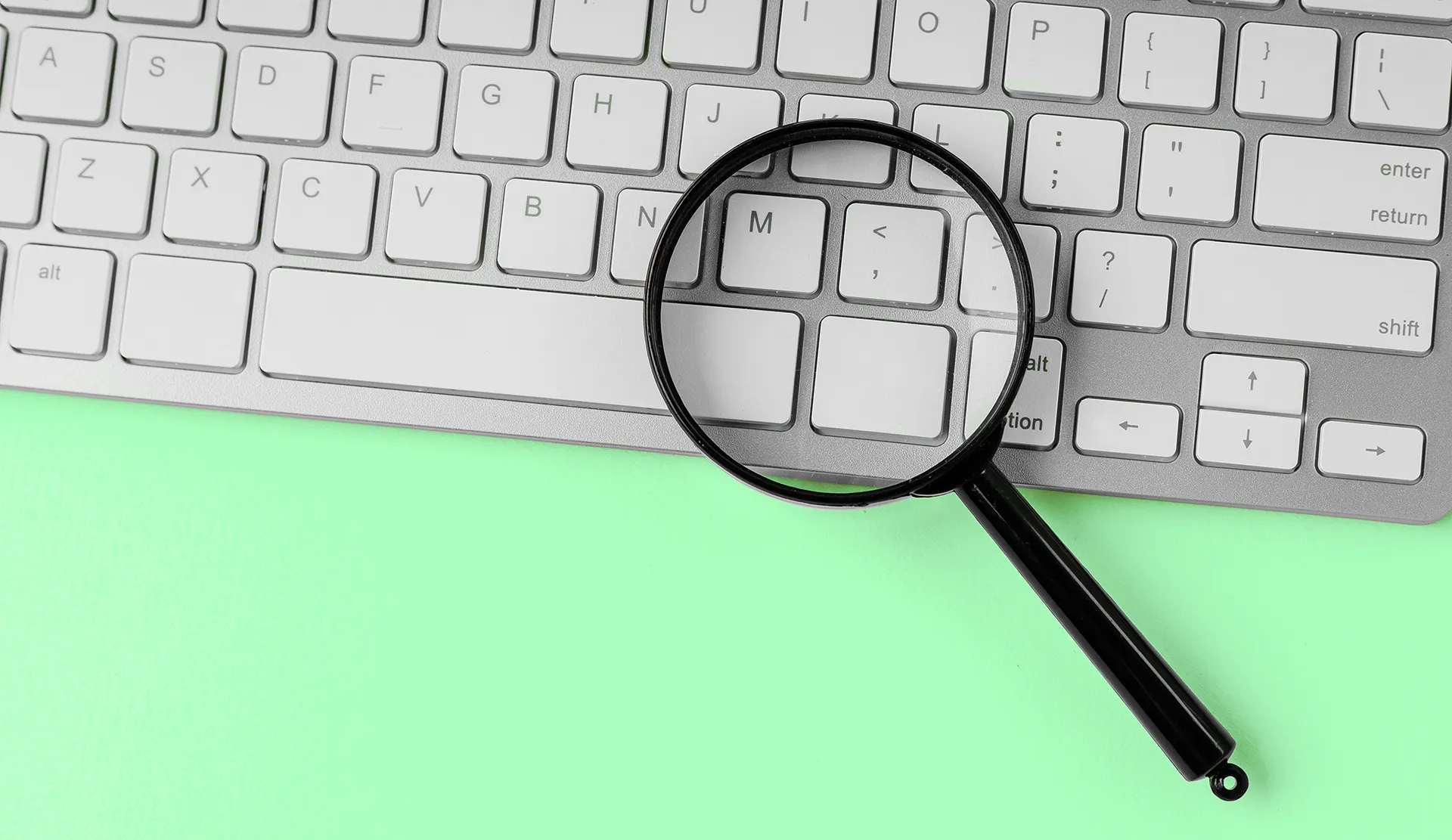 Magnifying glass placed over a keyboard, emphasizing the concept of search results and SEO.