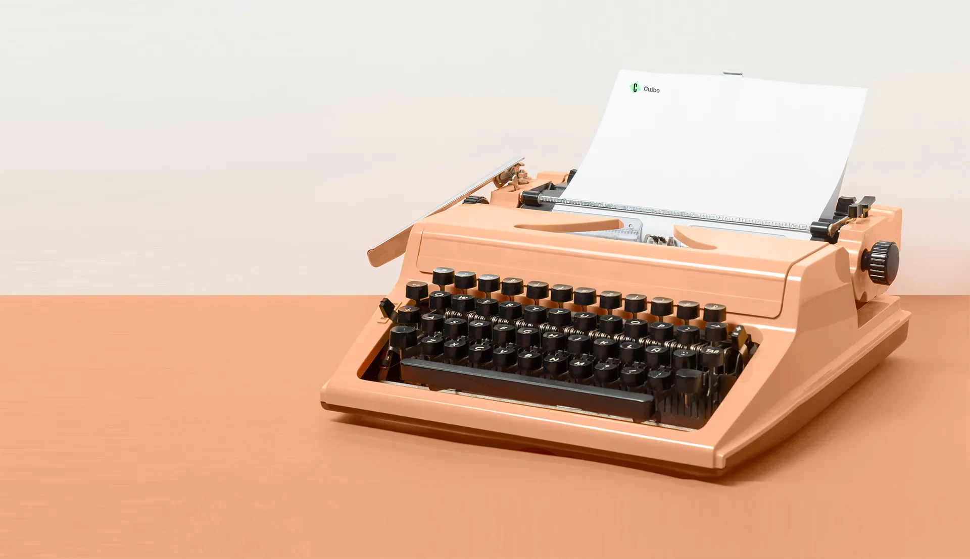 Vintage peach-colored typewriter with a blank sheet of paper inserted, placed on a minimalist desk, evoking a sense of retro communication and creativity.